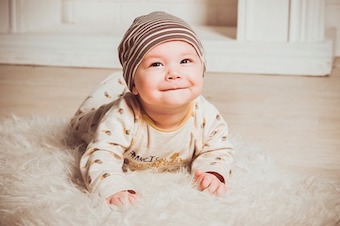 Baby liegt lächelnd auf dem Boden